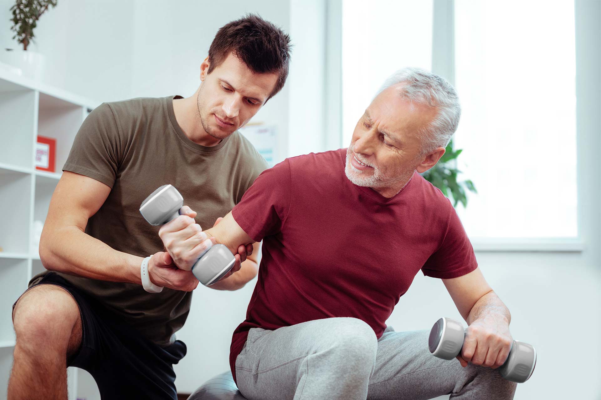 Bild: Physiotherapeut bei der Krankengymnastik mit älterem Herren